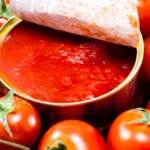 Immagine di una bottiglia di passata di pomodoro con un'etichetta evidenziata per i potenziali effetti negativi.